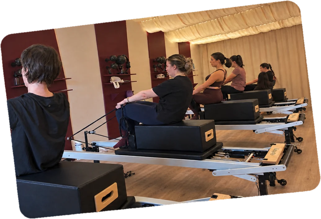 Un cours de Pilates Reformer en petit groupe chez Paulette, à Sartrouville : les Paulettes travaillent assises sur la box, devant les panneaux bordeaux