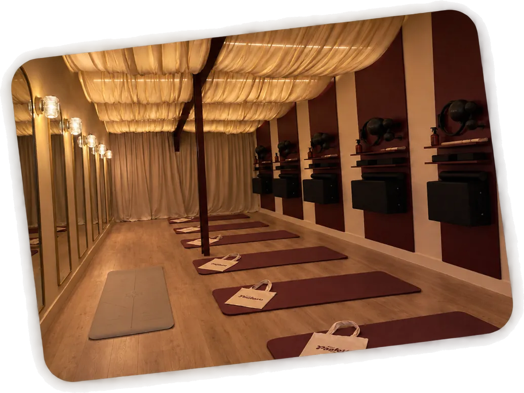 La salle de Chez Paulette à Sartrouville, prête pour le cours au tapis : les tapis bordeaux alignés, un sac Chez Paulette posé sur chacun, sous le plafond drapé et face aux miroirs dorés